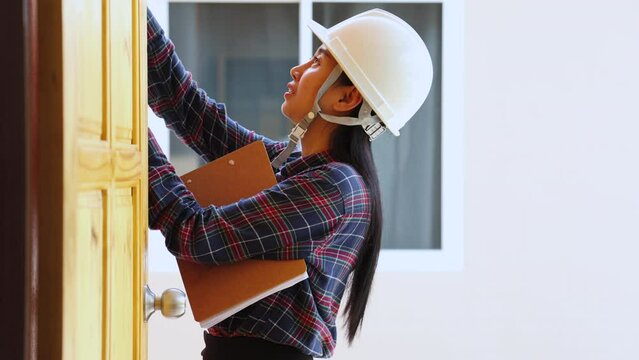 Young Asian inspector architect female working on construction site writing checklist electrical systems before sending new house to a developer or customer, inspection quality of real estate service