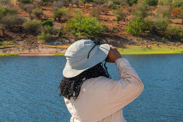 A tourist watching wildlife drinking at the edge of the Chobe River, while on a river cruise
