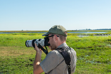 Tourist photographing wildlife while on a river cruise on the Chobe River