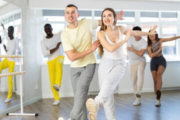 Motivated cheerful young adult couple, man and woman in casual sportswear dancing vigorous lindy...