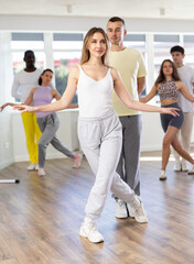 Fototapeta premium During rehearsal of reporting concert, guy and girlie participants of dance workshop perform figure waltz. Group training and rehearsal, preparation for competitions