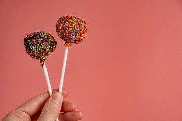 Woman hands holding pop cakes on pink background
