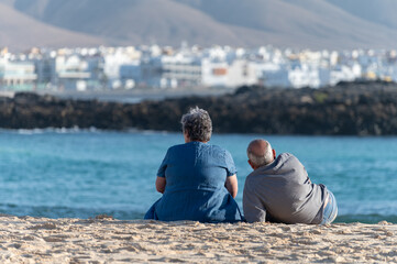 West coast of Fuerteventura island. Winter sea and sun vacation in El Cotillo touristic village, Canary islands, Spain. Unidenfitied old couple relaxing on white sandy beach La Concha..