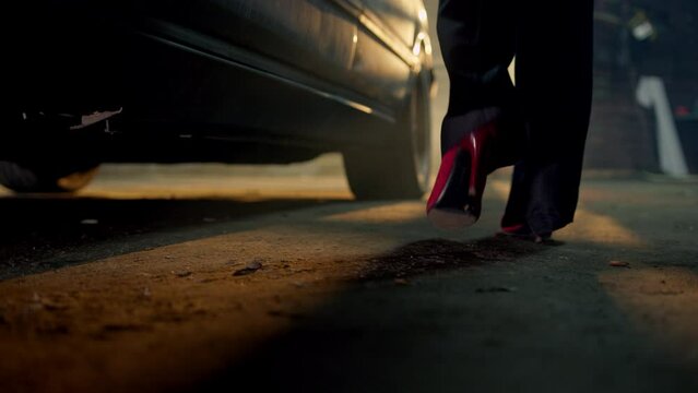 woman in red coat, her foot in heels visible, walks towards an old car in a dim garage. The vehicle, untouched for years, beckons her. She opens the door and settles into the driver's seat.
