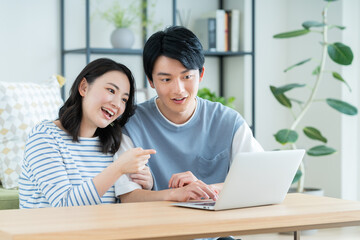 リビングでパソコンを見る仲良しの若い日本人夫婦