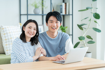 リビングでパソコンを見る仲良しの若い日本人夫婦