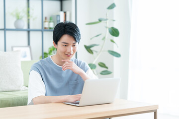 リビングでパソコンを見る若い日本人の男性