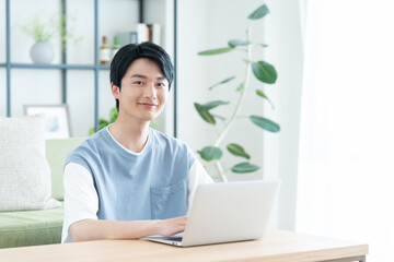 リビングでパソコンを見る若い日本人の男性