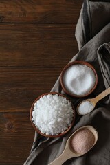 Different types of organic salt on wooden table, flat lay. Space for text