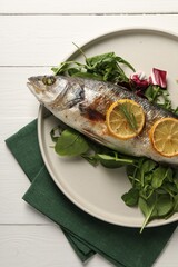 Baked fish with spinach and lemon on white wooden table, top view