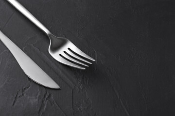 Beautiful cutlery set on black table, closeup. Space for text