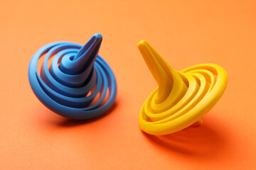 Blue and yellow spinning tops on orange background, closeup