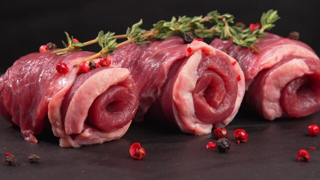 Lithe uncooked veal curls or marbled beef with thyme and himalayan peppercorns pepper close up. Meat products promo, butcher's video, culinary festival. Juicy beef. Flank slab for grinding