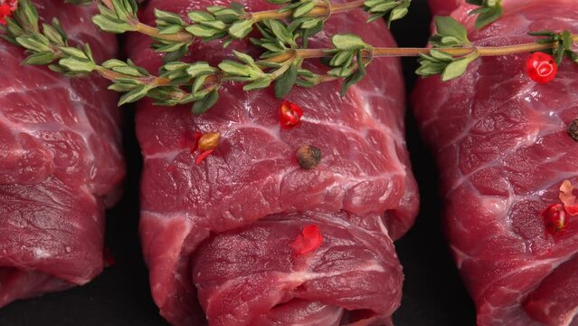 Sleek uncooked veal swirls or marbled beef with thyme and himalayan peppercorns pepper top view. Meat products ad, butcher's video, gastronomy showcase. Flank piece for grinding. Juicy red meat