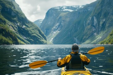 Man in Kayak Paddling through Water in a Scenic Fjord with Mountains