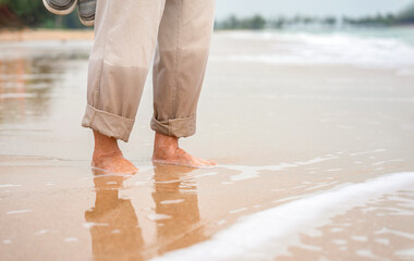 senior male barefoot on the sand beach,
