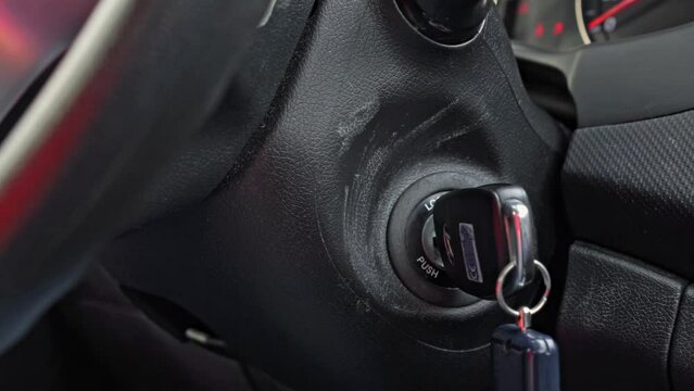 Man turns ignition key near steering wheel in car salon closeup. Father going on trip to buy Christmas tree at local marketplace in December morning