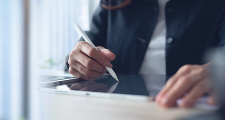 Businesswoman using stylus pen signing on digital tablet via mobile app, proofing e-document on...