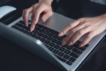 Closeup of business woman hands working and typing on laptop computer keyboard, surfing the internet, searching the information, global internet network