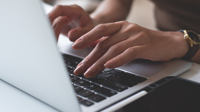 Woman hands typing on laptop computer, online working at coffee shop. Woman freelancer texting on laptop keyboard, surfing the internet, seraching the information on office table, close up