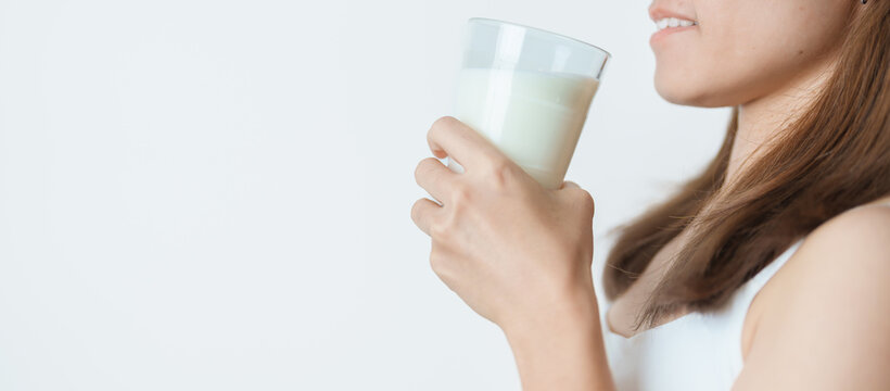 Milk drink and Daily Routine concept. Young woman Drinking milk with high calcium and nutrition at home, woman holding soy milk on glass with protein. Healthy, wellness and happy lifestyle