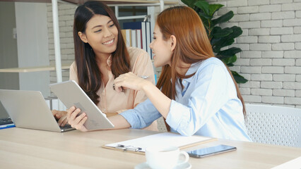 Two asian Female freelance reading financial graph charts Planning analyzing marketing data. Asian...