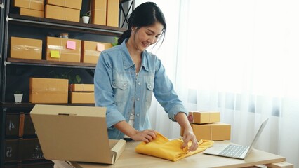 Fashion designer Women packing box on table checking goods quality package. Asian women startup small business at home office desk pack fashion design clothing. Asian woman packing startup business