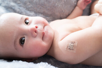 Band-aid with character on it on baby's right arm after vaccination