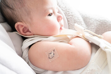 Band-aid with character on it on baby's right arm after vaccination