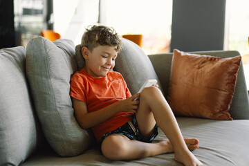 A boy with curly hair is deeply immersed in the game on the phone.