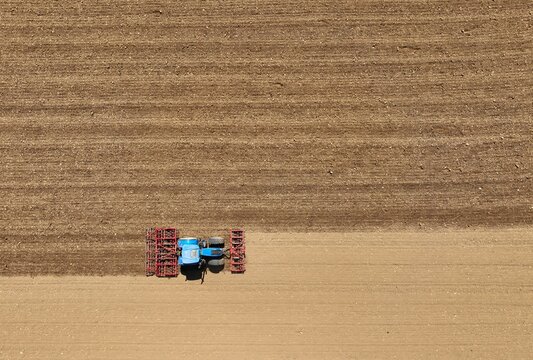 Un tracteur laboure et herse le champ avant la semence vue d'un drone