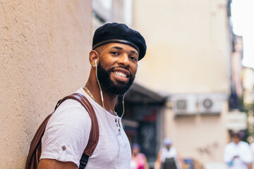 Stylish black man using smartphone and listening to music outdoors in the city