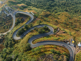 An aerial perspective showcases the intricate network of winding roads meandering through the hilly landscape at the break of dawn.