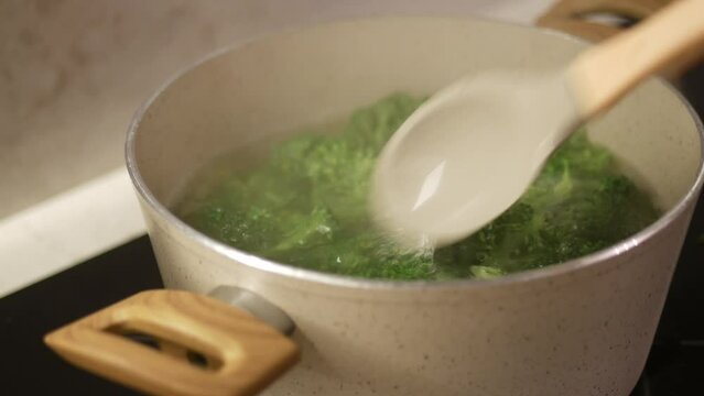 Fresh green broccoli florets gently boiling in a pot of water, 