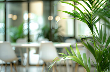 An office interior with glass walls, white chairs, tables, and green plants forms a blurred...