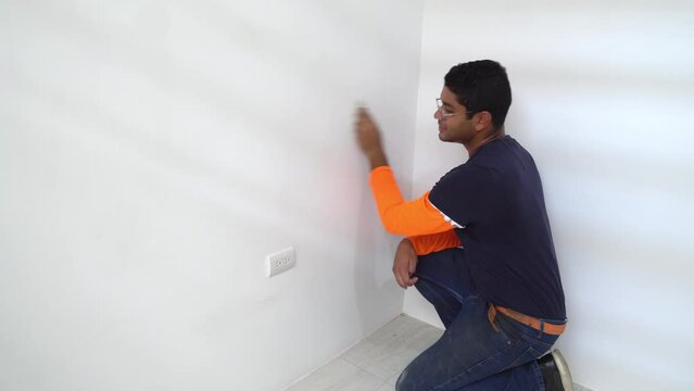 A Man is Wiping Down the Freshly Painted Interior Wall of the House - Static Shot