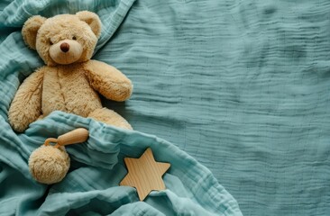 A teddy bear toy and a wooden toy are aligned on the left side of an empty teal bed sheet, leaving space for text or product placement in the center.