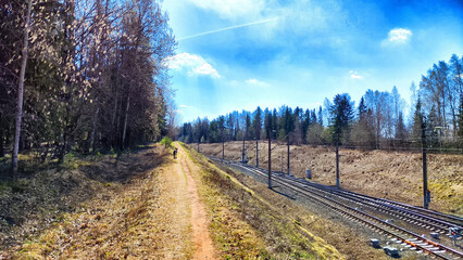 A railway with rails in autumn or spring on a sunny day. Landscape with trees and a slope