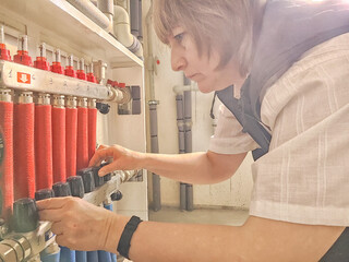 Female middle aged Technician Adjusting Industrial Water Filtration System. A woman services a water filtration unit
