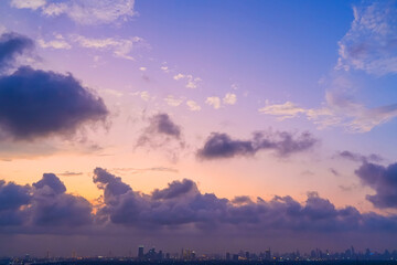 Yellow orange violet purple gradient with cumulus clouds over the city