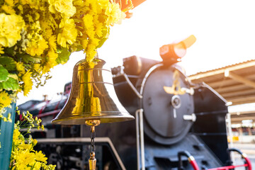 Gilded bell at the station against the backdrop of a historical steam locomotive leaving the station.