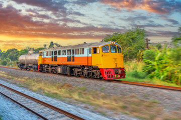 Diesel locomotive, increasing speed and leaving a plume of smoke, travels along the railway road...