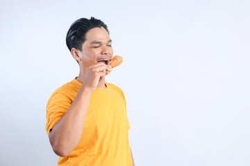 Side View od Young Man Enjoy Eating Crispy Fried Chicken Isolated on White Background  - obrazy, fototapety, plakaty