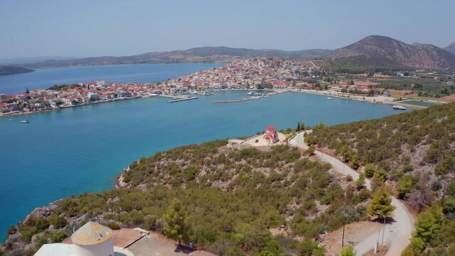 4k drone forward video (Ultra High Definition) of  Ermioni port and Greek Orthodox church St. Gerasimos on foreground. Exciting summer seascape of Myrtoa sea, Peloponnese, Greece, Europe.