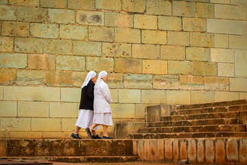 Nuns walking outside a convent, colonial style quarry stone church