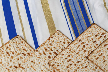 Matzah, a traditional unleavened bread, on a Tallit, a Jewish prayer shawl with stripes in different shades of blue, white, and gold. This scene is associated with the Jewish holiday of Passover
