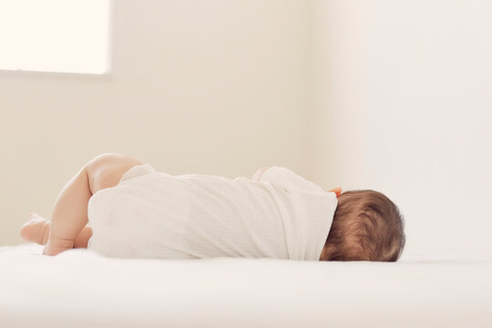 ベッドで眠る赤ちゃんの背中