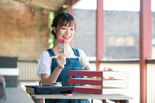 刷毛と手作りの箱を持って笑っている女性