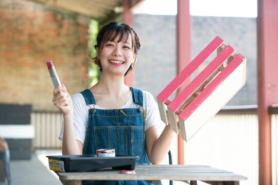 刷毛と手作りの箱を持って笑っている女性