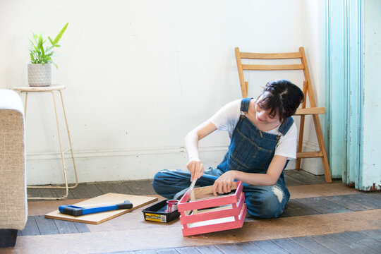 刷毛で箱にペンキを塗っている女性